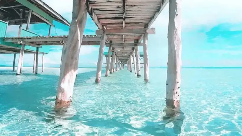 Looking along a wooden pier over clear turquoise water
