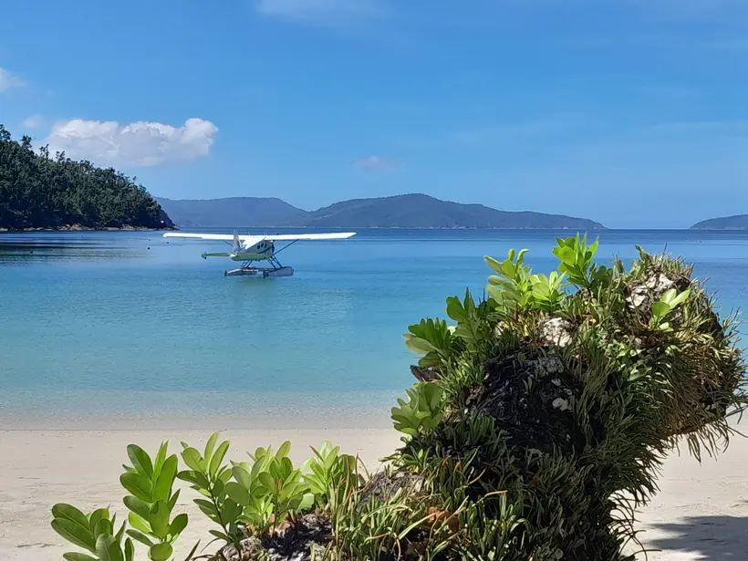 The seaplane resting in a calm bay seen from a quiet beach