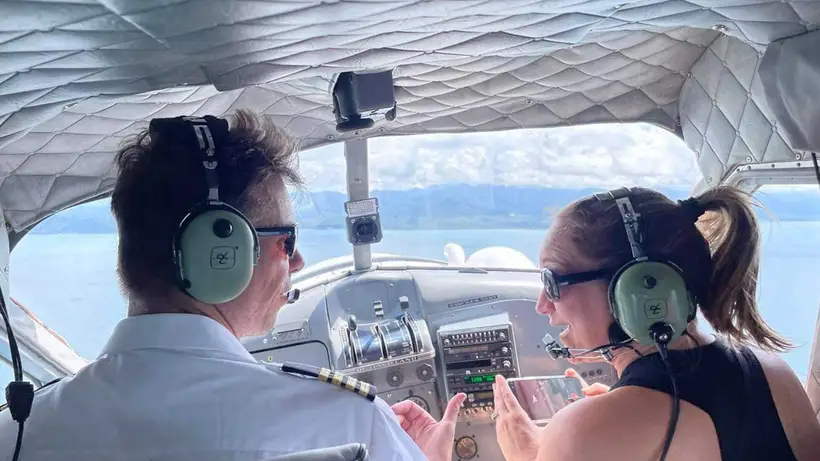 Captain and a guest in headsets in the Beaver's cockpit, sea ahead