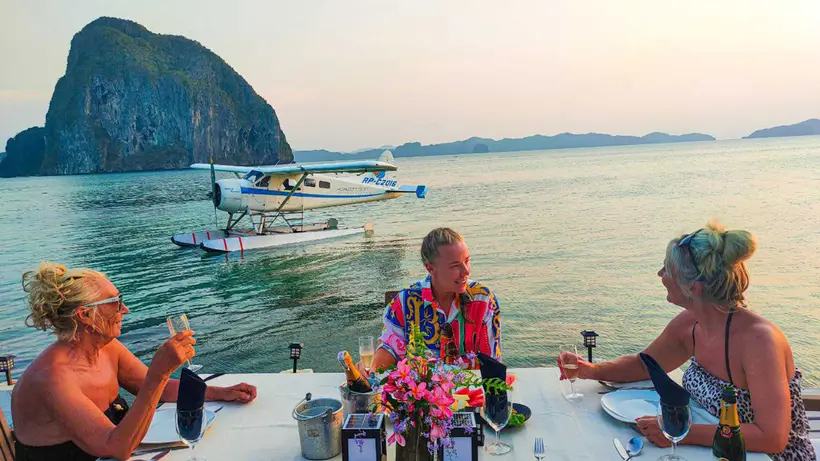 Guests toasting at a dinner table on a floating deck with the seaplane behind them