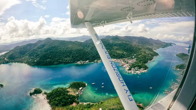 Islands and turquoise bays seen past the seaplane's wing strut during a scenic flight